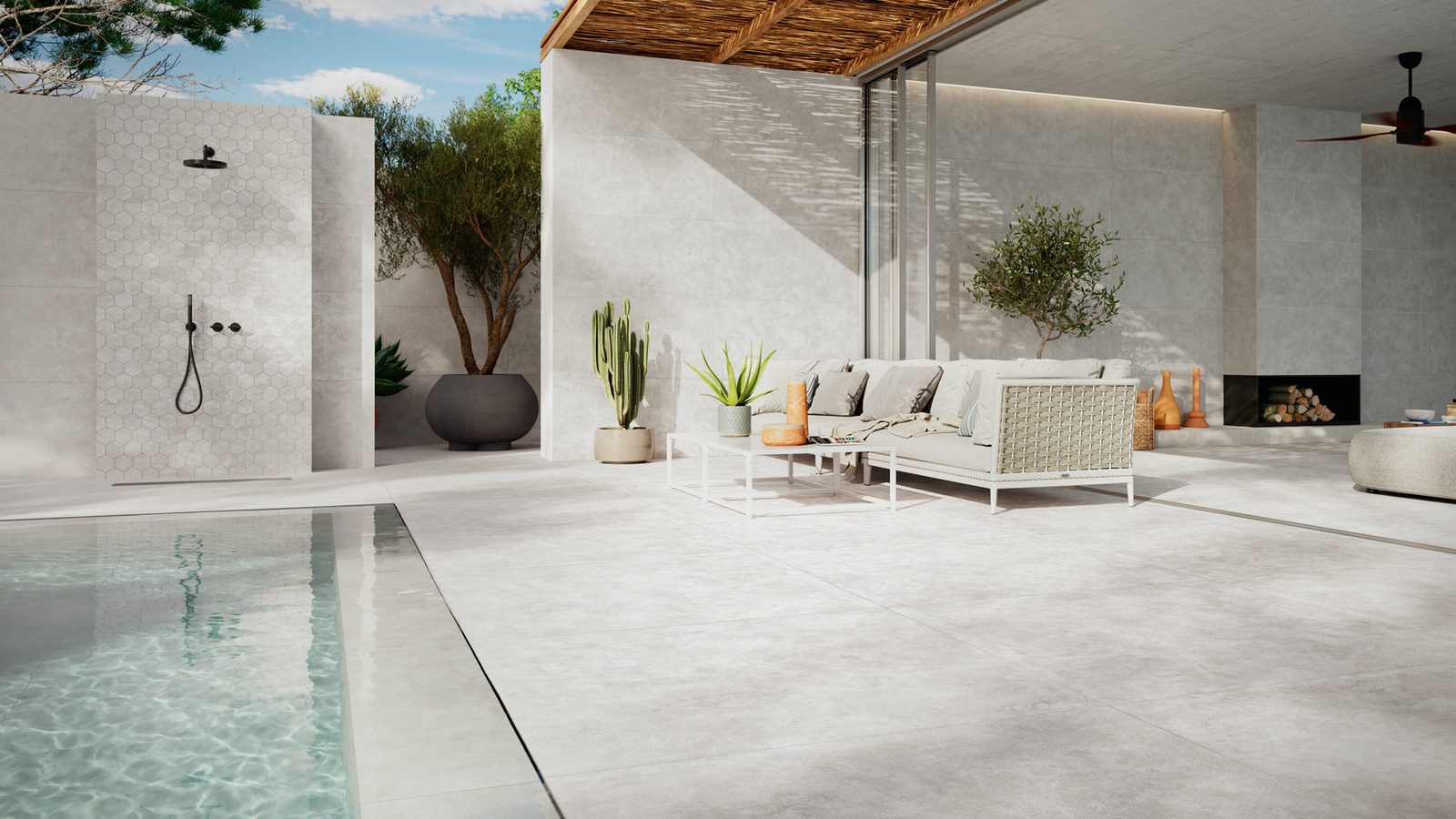 Een overdekt terras met grootformaat keramische tegels op de vloer en de wanden, met een zwembad op de voorgrond en een loungebank onder een rieten pergola